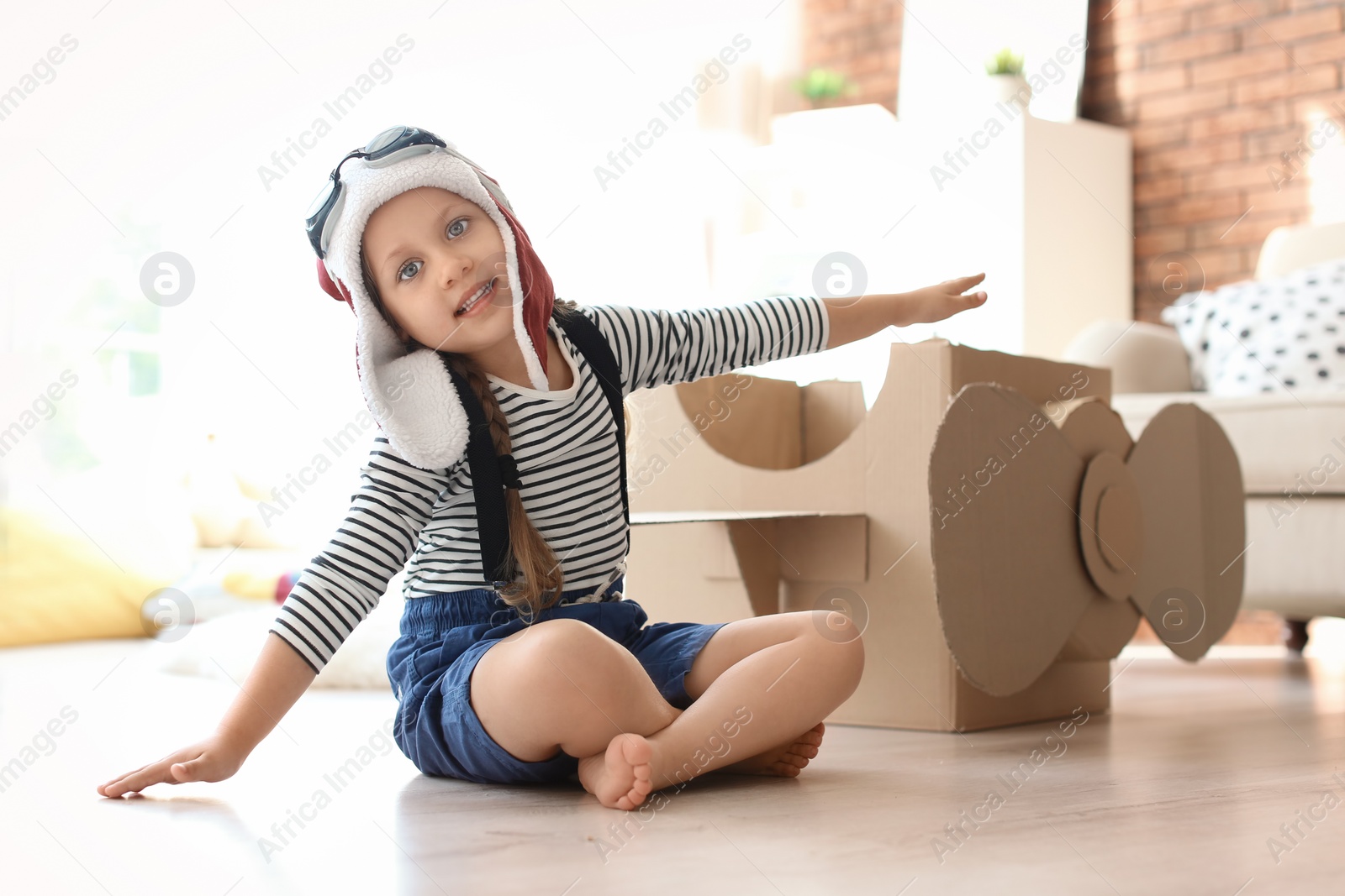 Photo of Adorable little child playing with cardboard plane at home