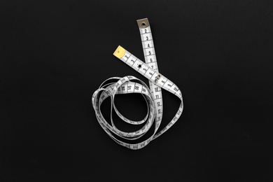 Photo of White measuring tape on black background, top view