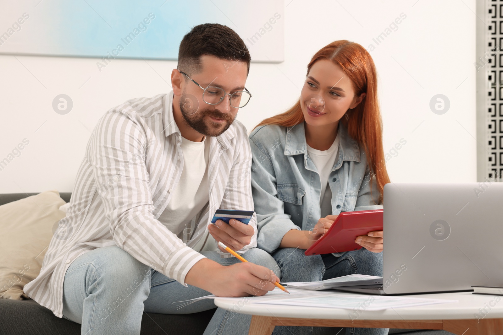 Photo of Couple filling in tax payment form at table in living room