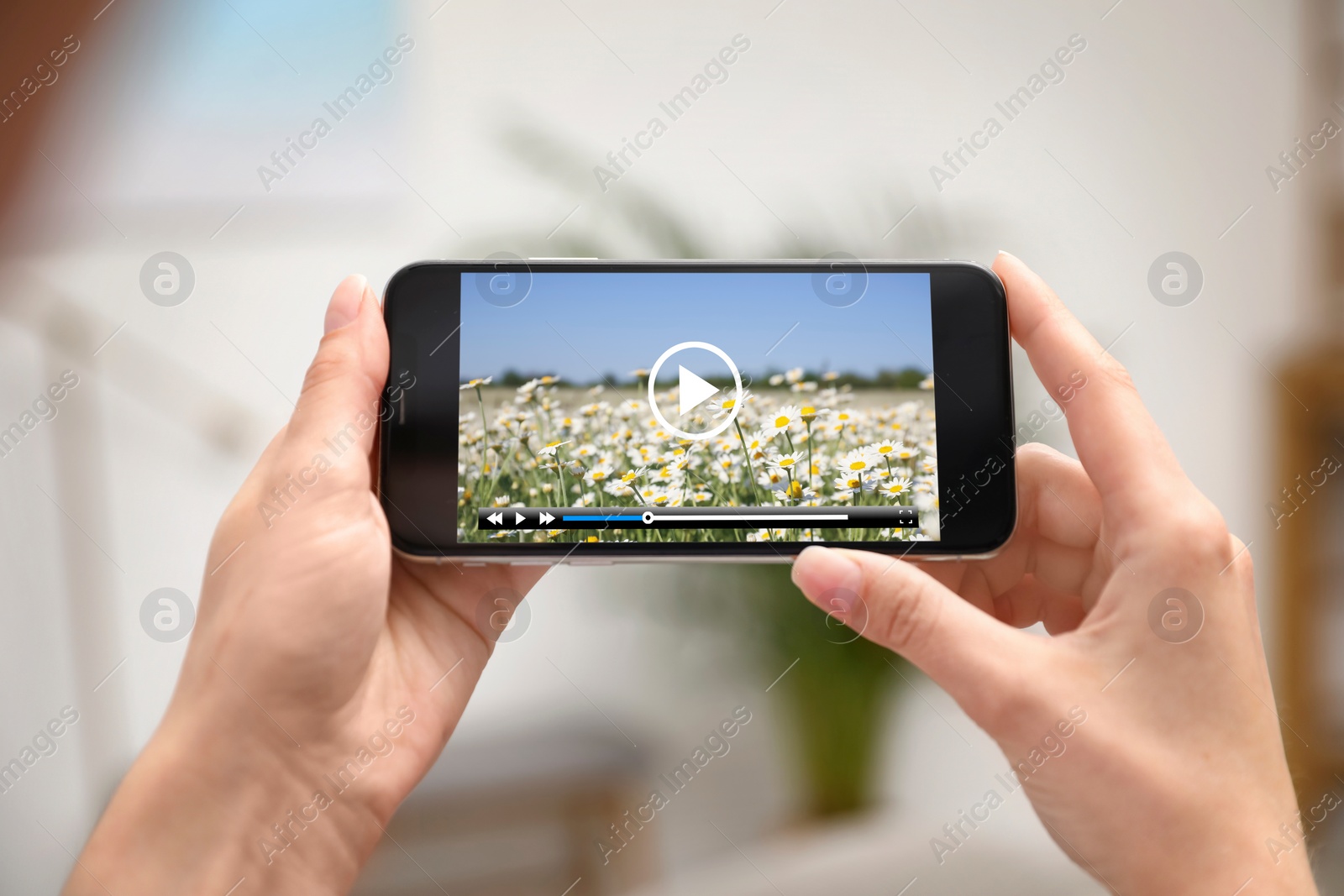 Image of Woman watching video on mobile phone at home, closeup