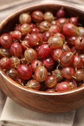 Photo of Bowl of fresh ripe gooseberries on table, closeup view