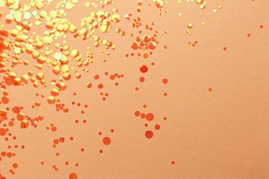 Photo of Shiny bright orange glitter on beige background, flat lay. Space for text