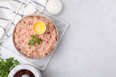 Photo of Flat lay composition with fresh raw minced meat, parsley and egg in bowl on light grey table. Space for text