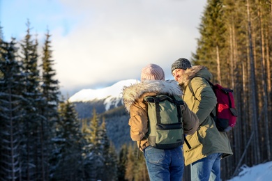 Photo of Couple with backpacks enjoying mountain view during winter vacation. Space for text