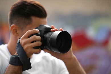 Photographer taking picture with professional camera outdoors, focus on device