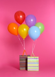 Paper bags with bright air balloons on color background