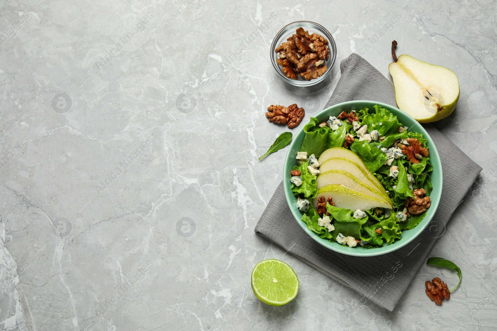 Photo of Tasty salad with pear slices and ingredients on light grey table, flat lay. Space for text