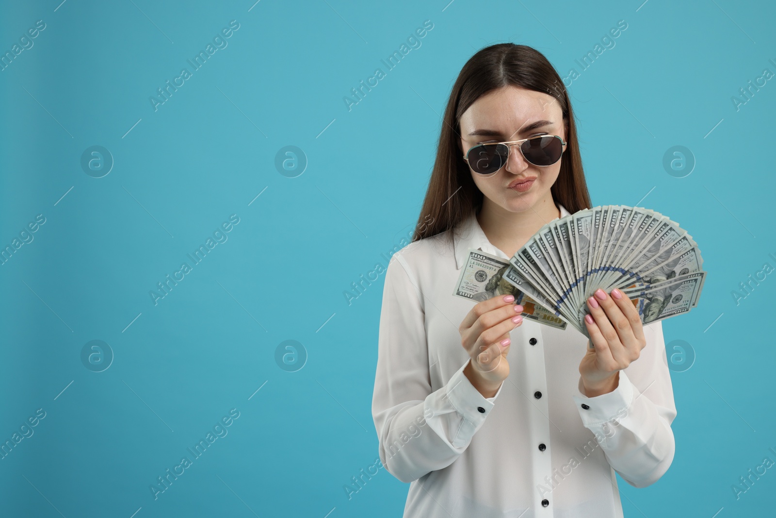 Photo of Woman with dollar banknotes on light blue background, space for text