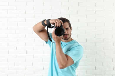 Young professional photographer taking picture near brick wall