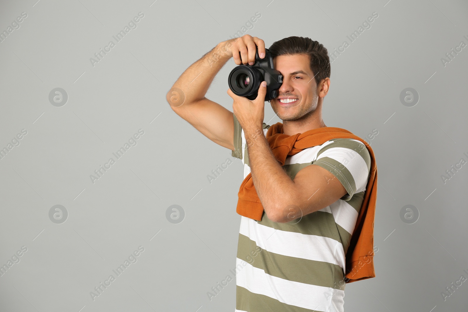 Photo of Professional photographer working on light grey background in studio. Space for text