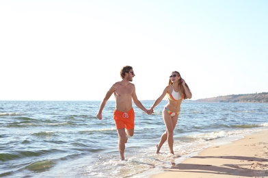 Photo of Happy young couple in beachwear running together on seashore