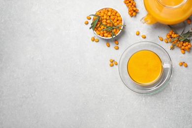 Sea buckthorn tea and fresh berries on light table, flat lay. Space for text