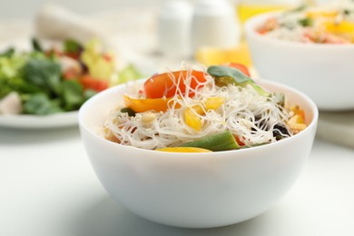 Tasty cooked rice noodles with vegetables on white table