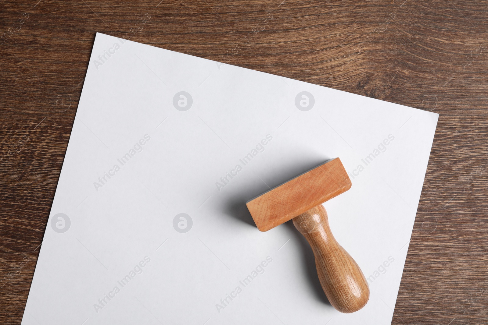 Photo of Blank sheet of paper and visa stamp on wooden table, top view