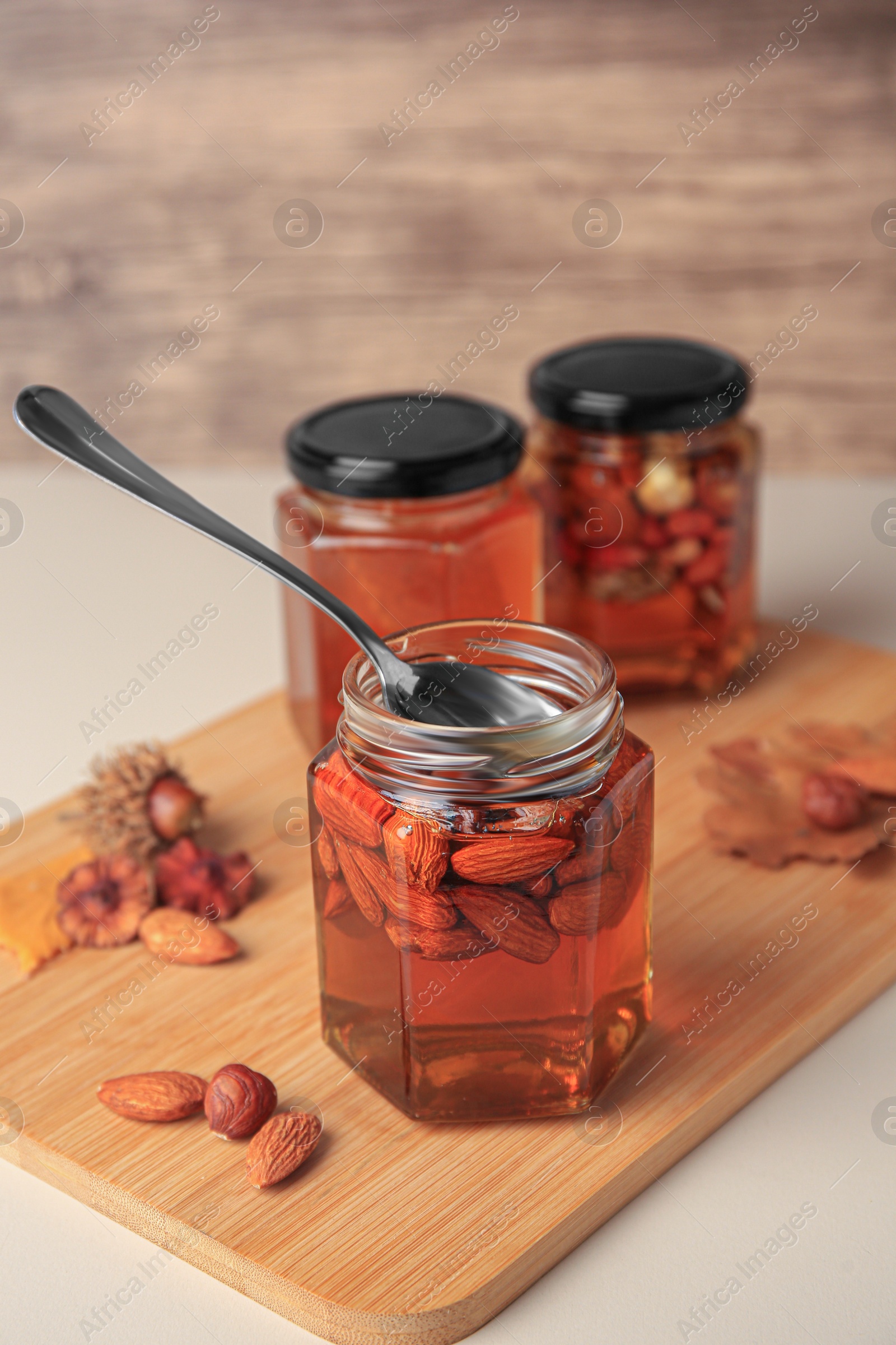 Photo of Jars with different nuts and honey on beige table