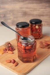 Photo of Jars with different nuts and honey on beige table
