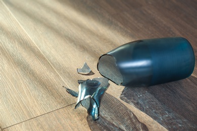 Photo of Broken blue glass vase on wooden floor. Space for text