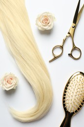 Hairdresser tools. Blonde hair lock, scissors, brush and flowers on white backpack, flat lay