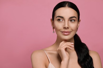 Photo of Young woman wearing elegant pearl earrings on pink background, space for text