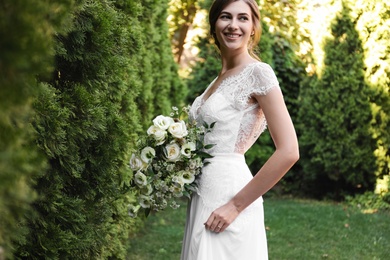 Gorgeous bride in beautiful wedding dress with bouquet outdoors