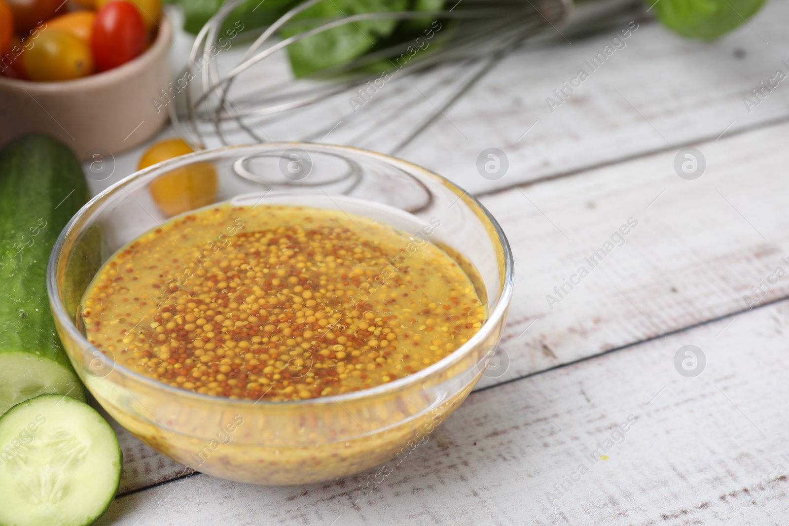 Photo of Tasty vinegar based sauce (Vinaigrette) in bowl and cucumber on wooden rustic table, closeup. Space for text