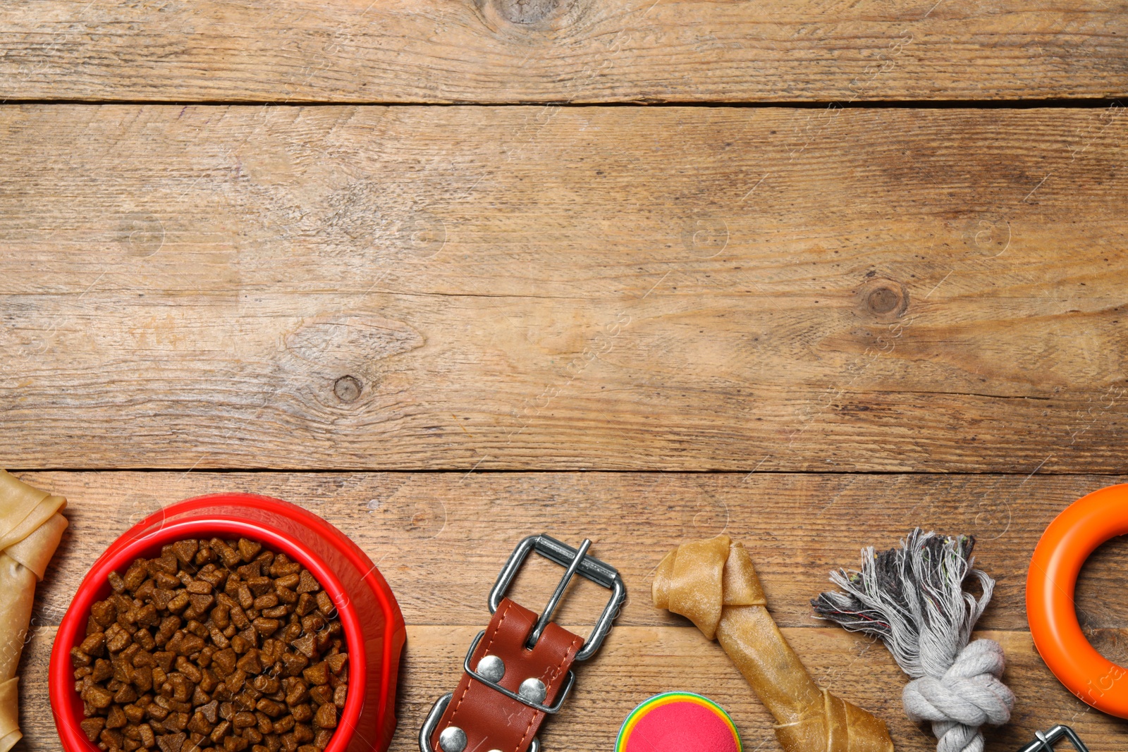 Photo of Flat lay composition with dog collar, toys and food on wooden table. Space for text