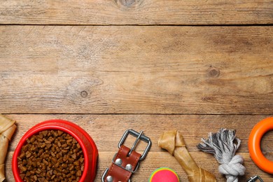 Flat lay composition with dog collar, toys and food on wooden table. Space for text