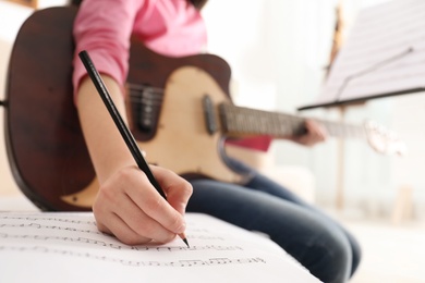 Photo of Child with guitar writing music notes at home, closeup