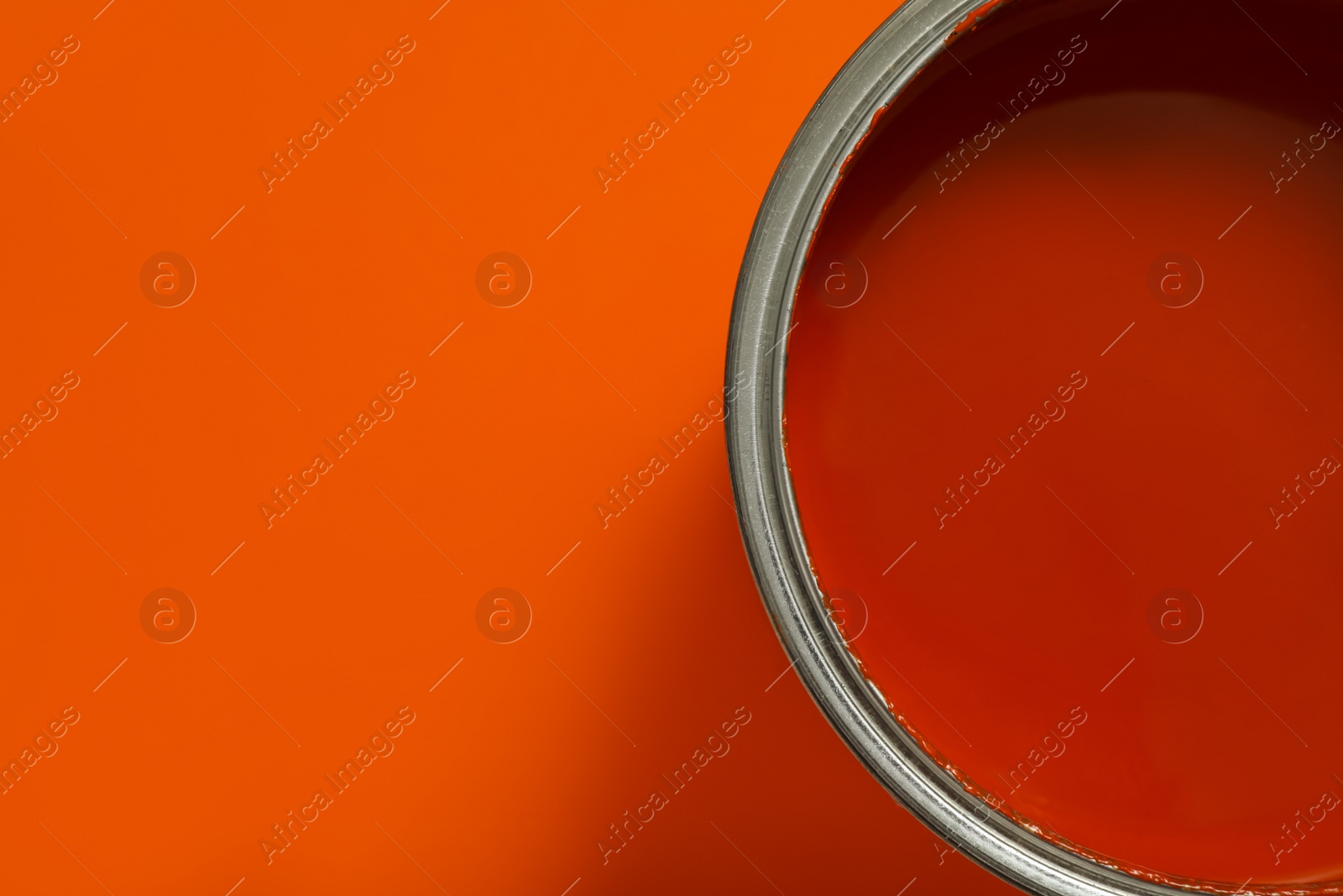 Photo of Can of orange paint on color background, top view. Space for text