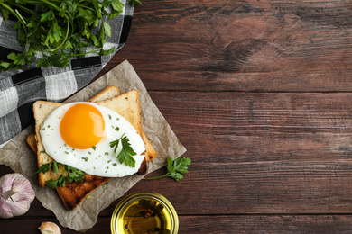 Tasty fried egg with toasts and parsley on wooden table, flat lay. Space for text