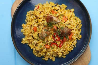Photo of Delicious pilaf with meat, carrot and chili pepper on light blue wooden table, top view