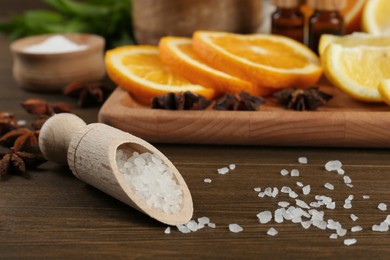 Photo of Scoop with sea salt and fresh ingredients on wooden table, closeup