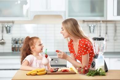 Photo of Mother and daughter preparing delicious milk shake in kitchen