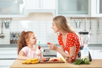 Mother and daughter preparing delicious milk shake in kitchen