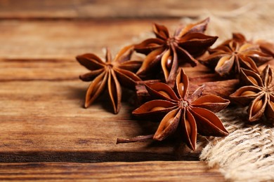 Photo of Aromatic anise stars and cinnamon sticks on wooden table, closeup