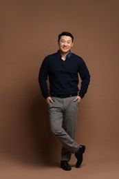 Full length portrait of happy man on brown background