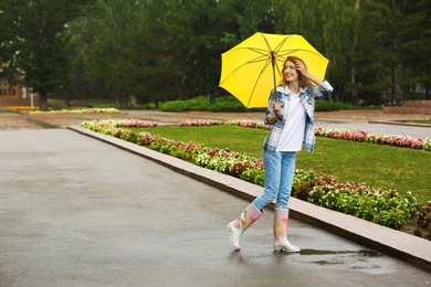 Happy young woman with umbrella under rain in park