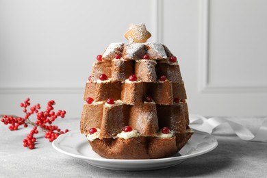 Photo of Delicious Pandoro Christmas tree cake with powdered sugar and berries on white table