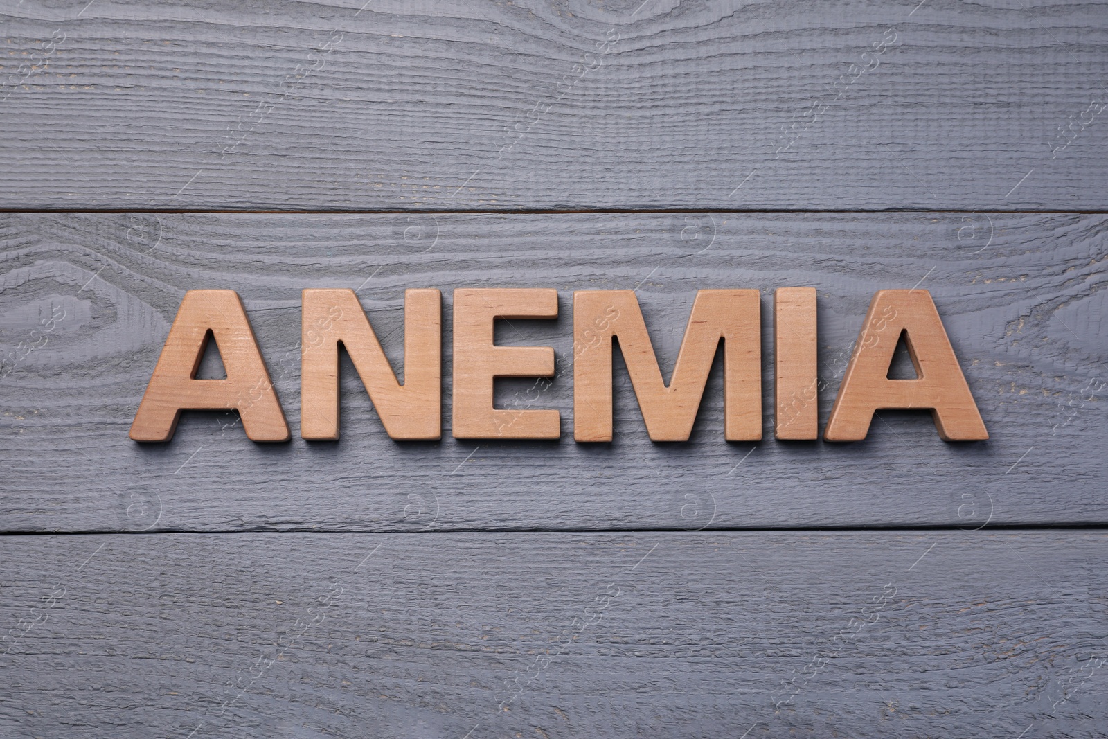 Photo of Word Anemia made with wooden letters on grey table, flat lay