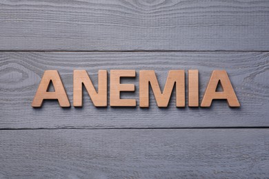 Photo of Word Anemia made with wooden letters on grey table, flat lay