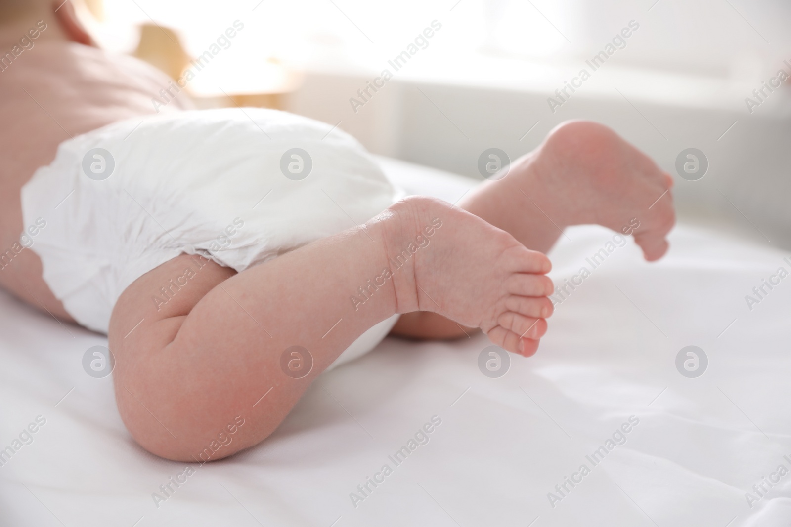 Photo of Cute little baby in diaper on bed, closeup