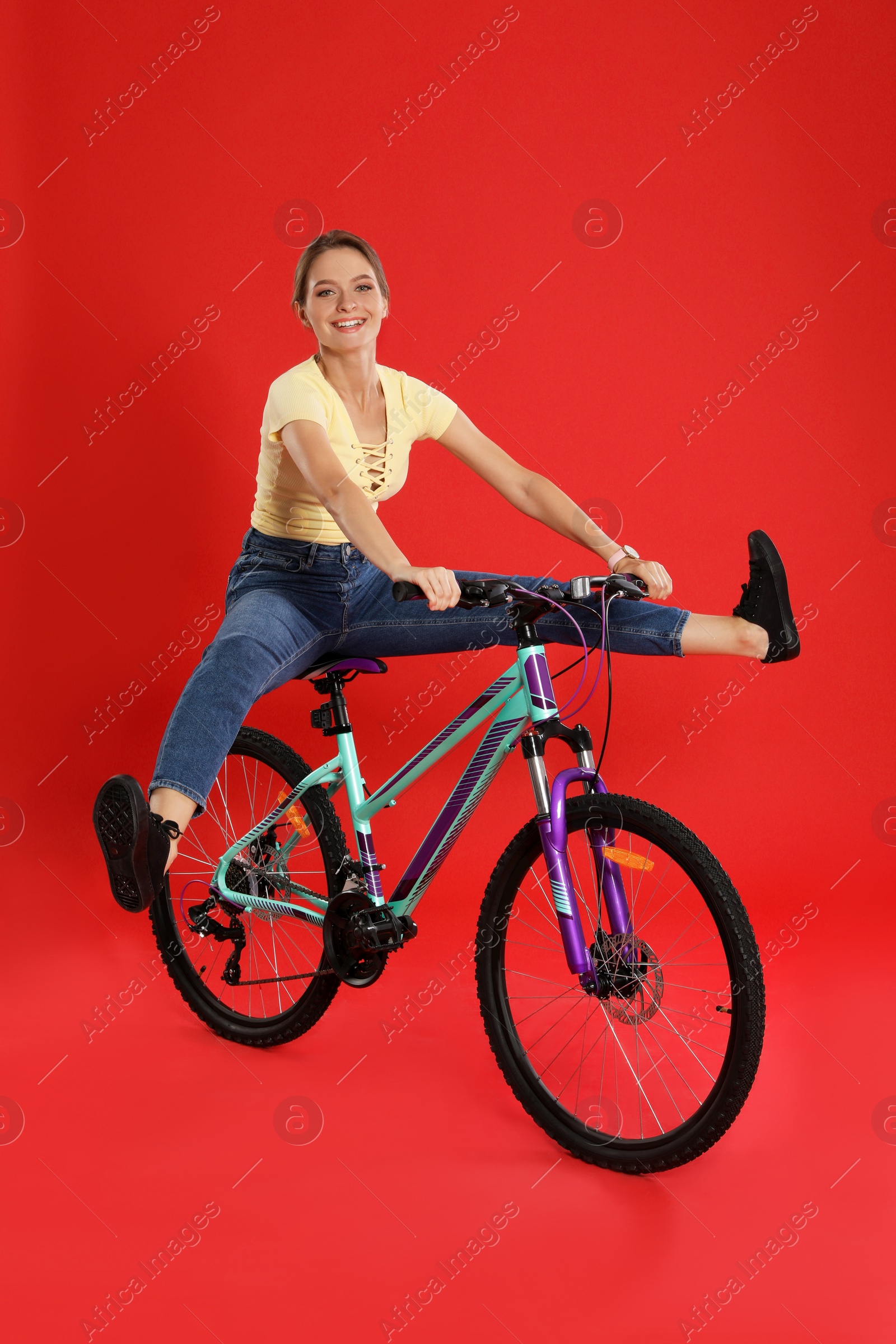 Photo of Happy young woman riding bicycle on red background