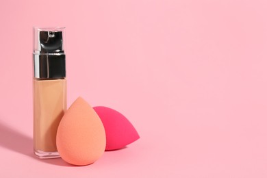 Photo of Makeup sponges and skin foundation on pink background. Space for text