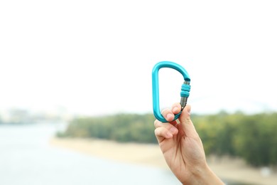 Photo of Woman holding metal carabiner outdoors, closeup. Space for text