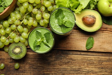 Photo of Green smoothie in glasses and fresh ingredients on wooden table, flat lay