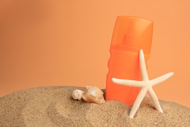 Photo of Sand with bottle of sunscreen, starfish and seashells against orange background, space for text. Sun protection