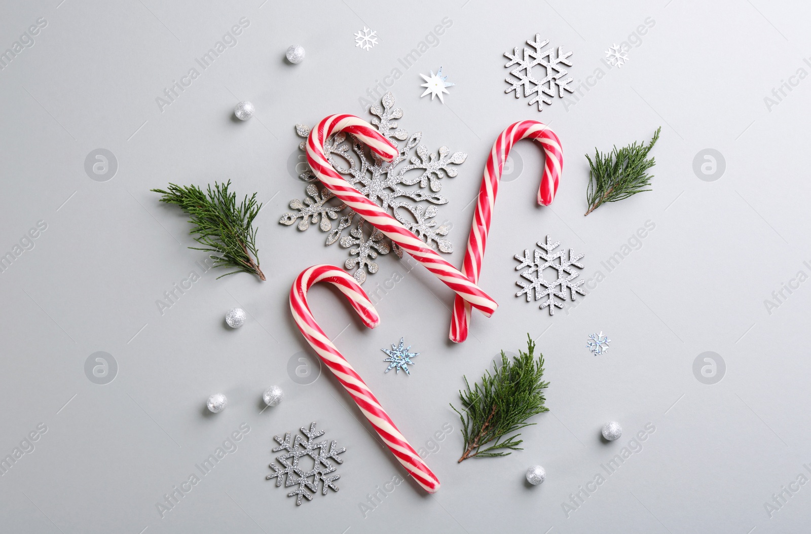 Photo of Flat lay composition with candy canes and Christmas decor on grey background