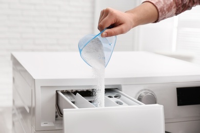 Photo of Woman pouring powder into drawer of washing machine indoors, closeup. Laundry day