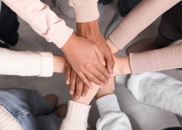 Photo of Group of multiracial people joining hands together indoors, top view