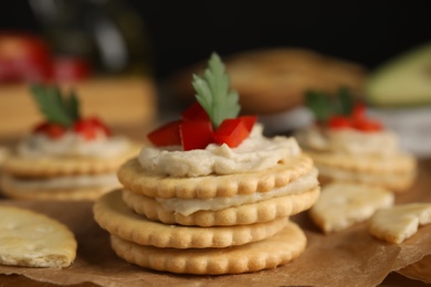 Photo of Delicious crackers with humus, bell pepper and parsley on paper, closeup